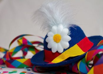 Clownhut mit Blume und Federn zwischen Konfetti und Luftschlangen